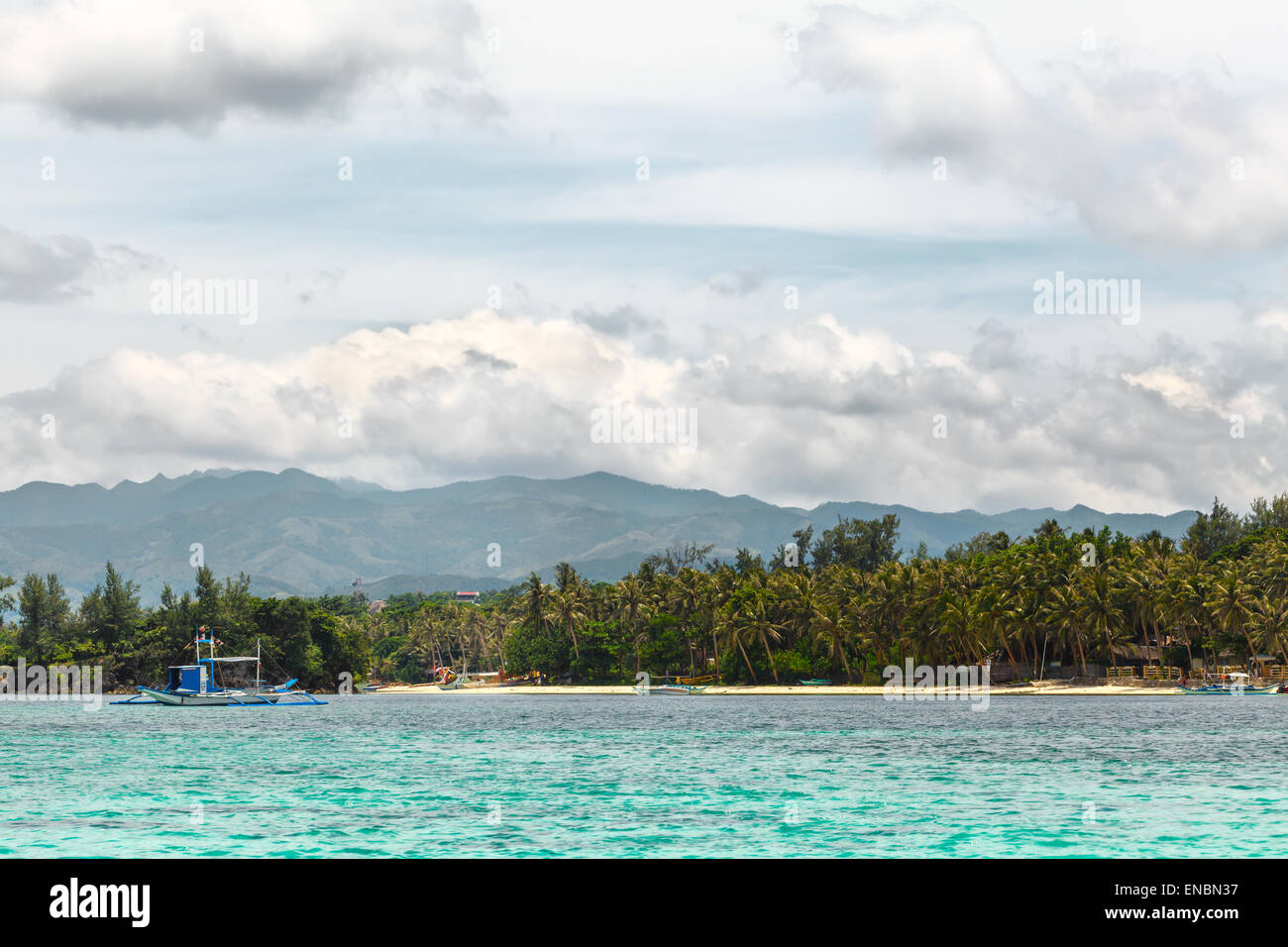 Grüne tropische Insel mit Palmen auf gelben Strand mit Steinen im blauen Meer, weißes Schiff Philippinen Boracay island Stockfoto
