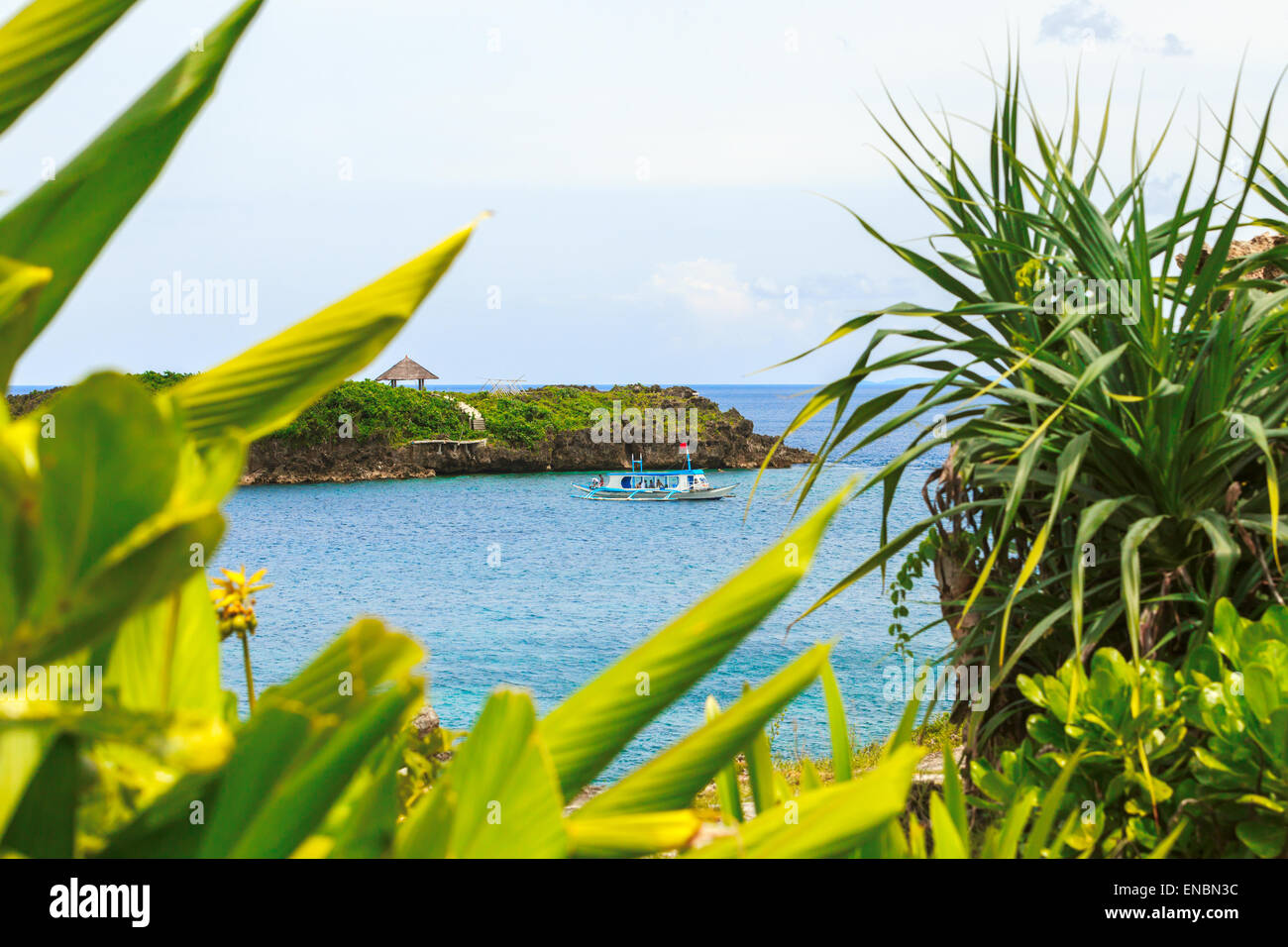 Grüne tropische Insel mit Palmen auf gelben Strand mit Steinen im blauen Meer, weißes Schiff Philippinen Boracay island Stockfoto