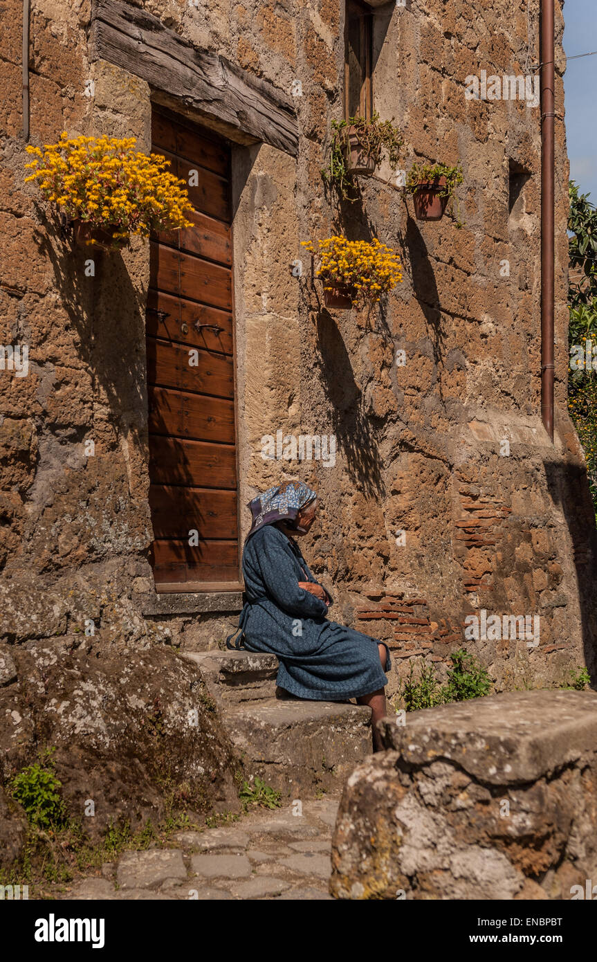 Nachdenkliche Frau sitzt auf der Schritte in Civita di Bagnoregio, Italien Stockfoto