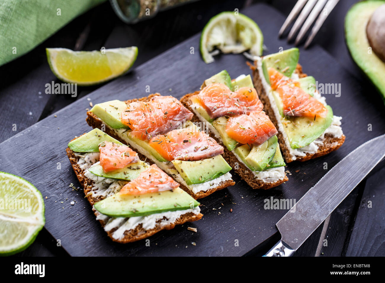 Sandwich mit Avocado und geräuchertem Lachs auf einer hölzernen Tafel Stockfoto