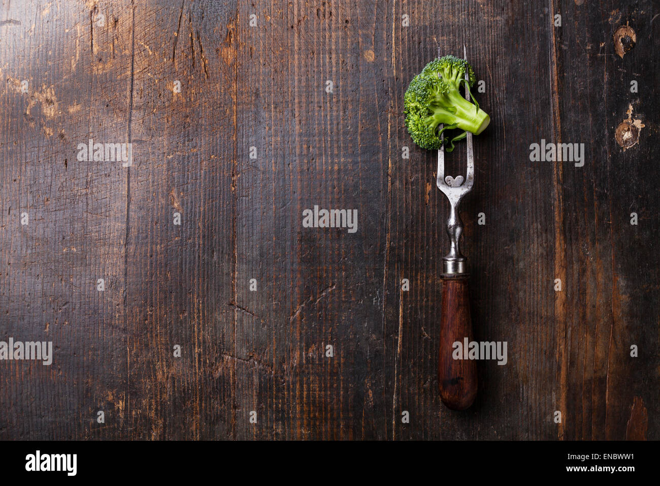 Frischer Brokkoli auf Fleischgabel auf dunklem Holz Stockfoto