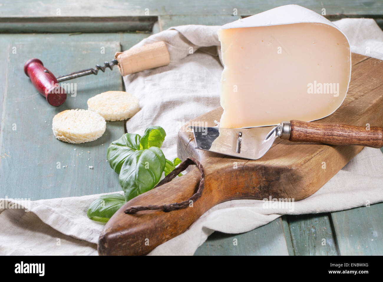 Ziegenkäse, serviert mit frischem Basilikum und Brot auf Holzbrett über Türkis Holztisch. Stockfoto