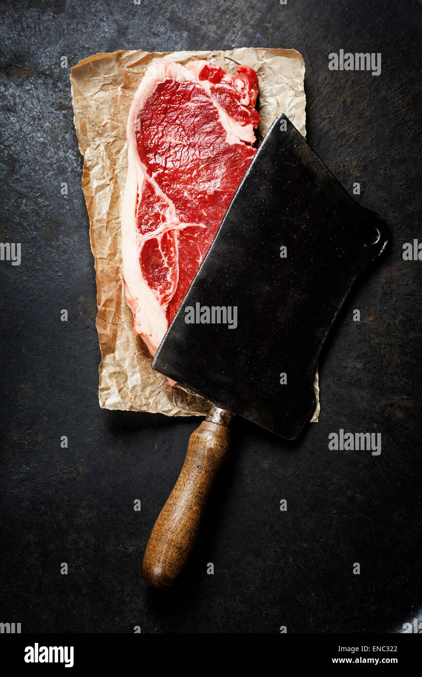 Vintage Cleaver und rohes Rindfleischsteak auf dunklem Hintergrund Stockfoto