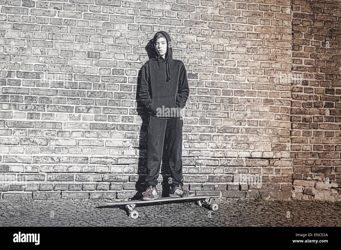 Schwarz und weiß zu schießen, von einem Teenager Hoodie steht auf ein langes Brett Stockfoto