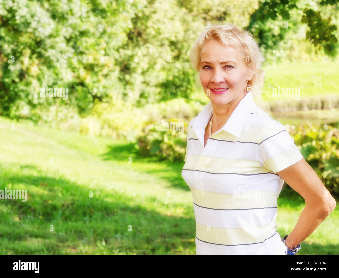Porträt einer Frau mittleren Alters in einem Park an einem sonnigen Tag Stockfoto