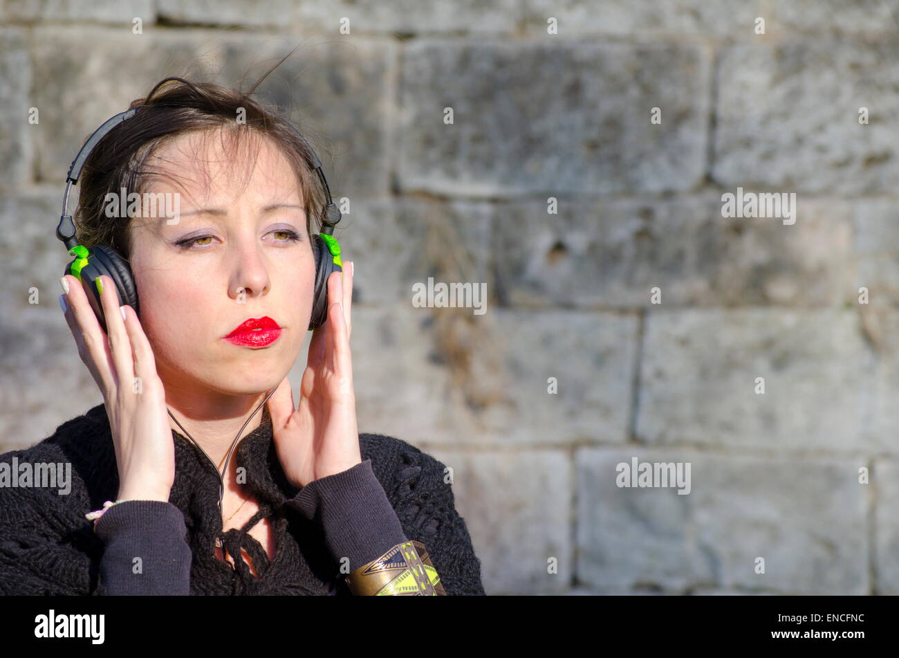 Nachdenklich Brünette anhören von Musik über einen Kopfhörer im freien Stockfoto