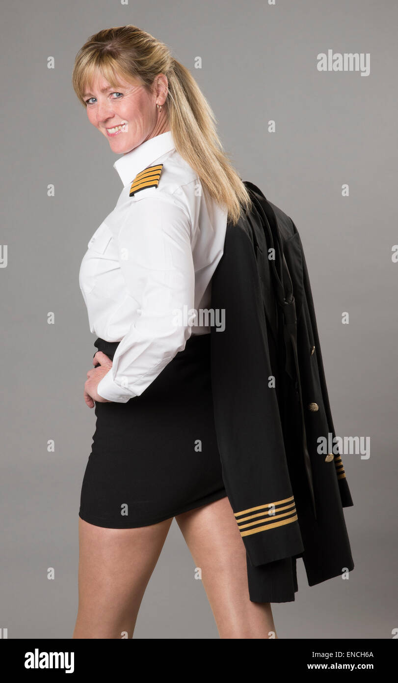 Attraktive weibliche Airline Officer trägt einen kurzen Rock und ihrer Uniformjacke über der Schulter tragen Stockfoto