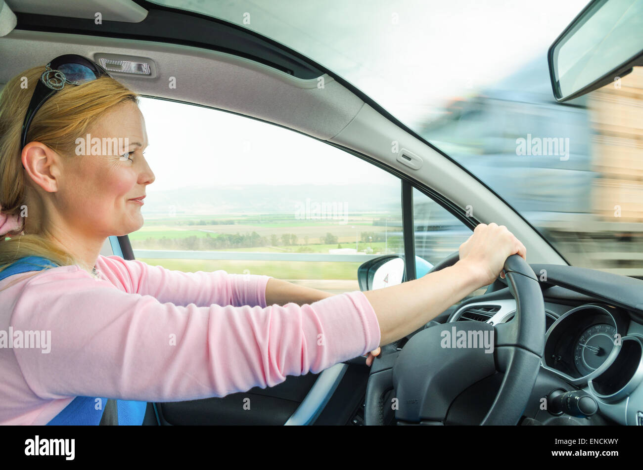 Attraktive Erwachsene Frau sicher und vorsichtig fahren Auto s unterwegs. Innen Auto Foto mit hoher Geschwindigkeit entgegenkommenden LKW truck Stockfoto