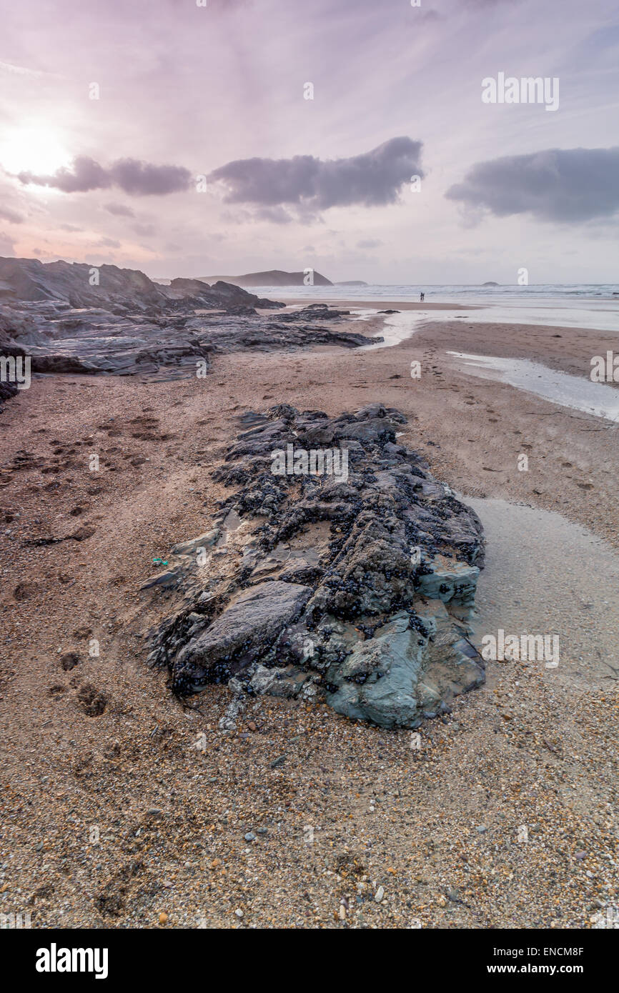 Polzeath Strand Cornwall England Vereinigtes Königreich als die Sonne setzt sich zwischen den Felsen Stockfoto