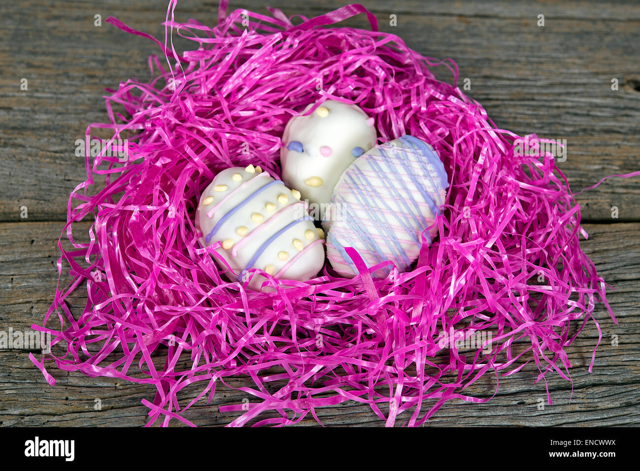 Dekorative Ostereier Cookies in knalligem Pink grasbewachsenen nisten auf rustikalen Holz. Stockfoto