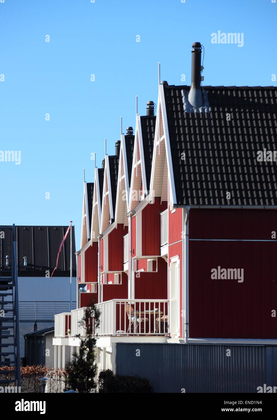 Mietshäuser in rotem Holz mit blauem Himmel Stockfoto