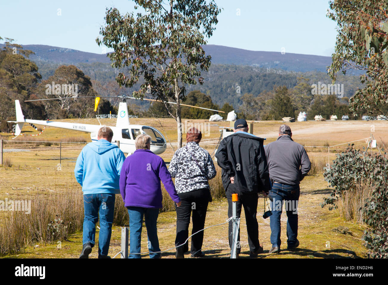 Gruppe von Menschen, die unterwegs für einen Helikopterflug über Cradle Mountain National Park, Tasmanien, Australien Stockfoto