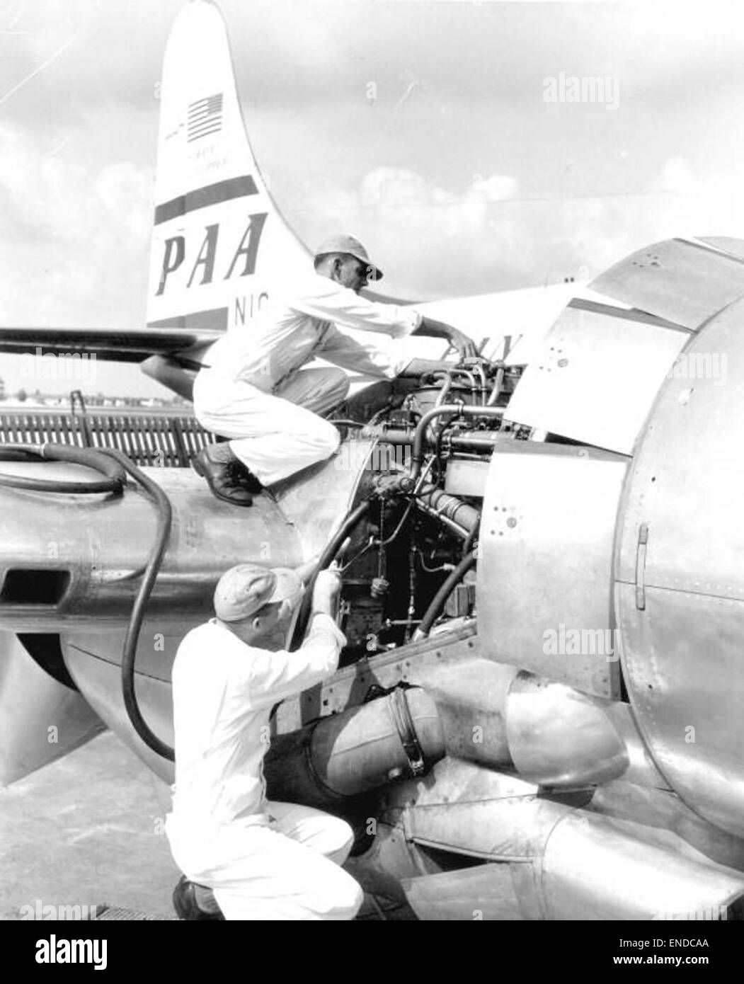Dieses Foto zeigt Techniker, die Motorwartungen an einem panamerikanischen Flugzeug in Miami durchführen. Das Bild zeigt die technischen Aspekte der Flugzeugwartung und der Luftfahrtindustrie Mitte des 20. Jahrhunderts. Stockfoto
