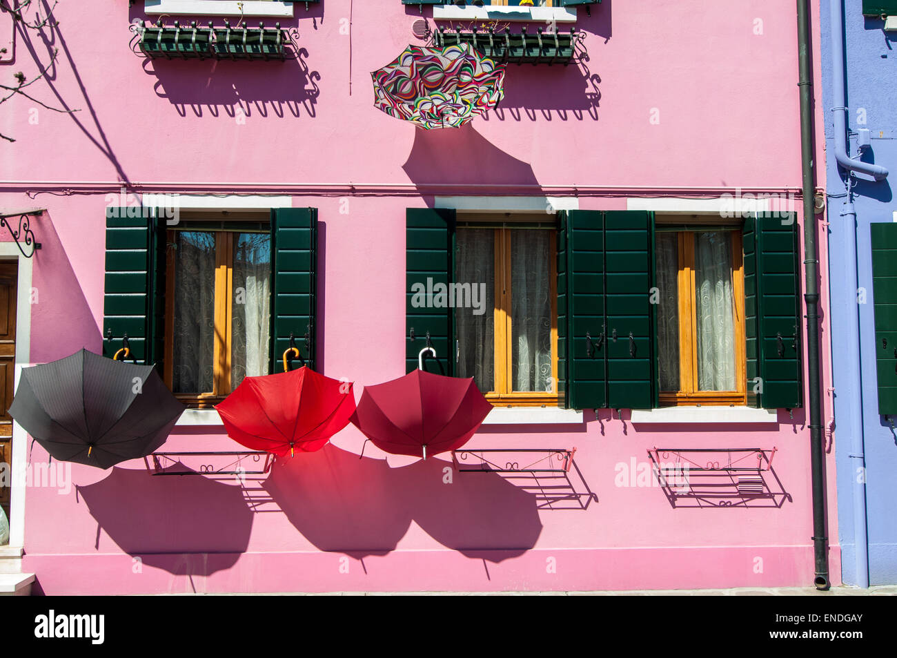 Sonnenschirme bei Windows von einem rosa Haus mit Sonne und Schatten trocknen aufgehängt Stockfoto