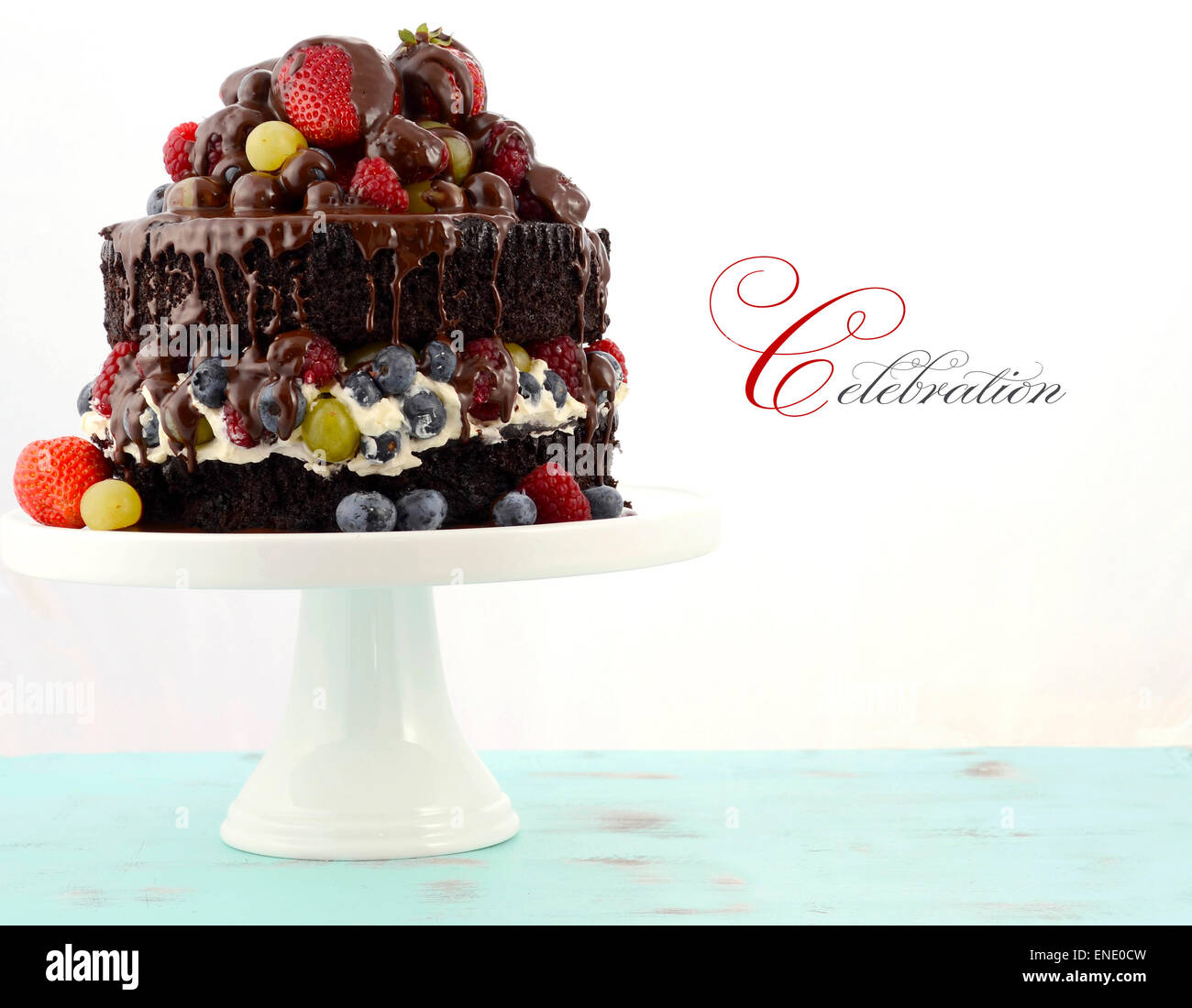 Herrlich göttlichen chocolate Cake mit Erdbeeren, Blaubeeren, Himbeeren und Trauben und Creme auf blass blauen shabby chic Reiter Stockfoto