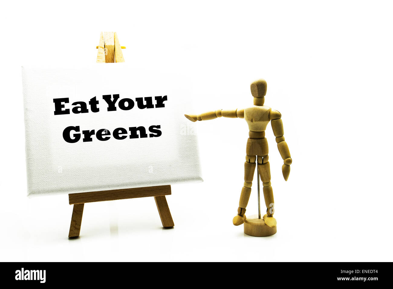 Hölzerne Mann mit weißen Tafel zeigt auf Worte "Essen Ihre grünen" gesundes Essen Heide Gemüse pflegen Ihren Körper Lebensstil Stockfoto