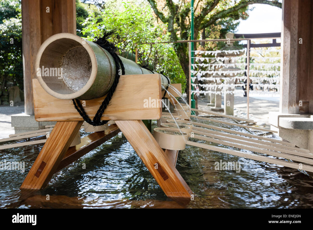 Schließen Sie Schöpfkellen und die Bambuspfeife auf einem Böll, mit Wasser Gießen aus Löchern in die Chozuya Wasserreinigungsfont an einem japanischen schintoistischen Schrein. Stockfoto