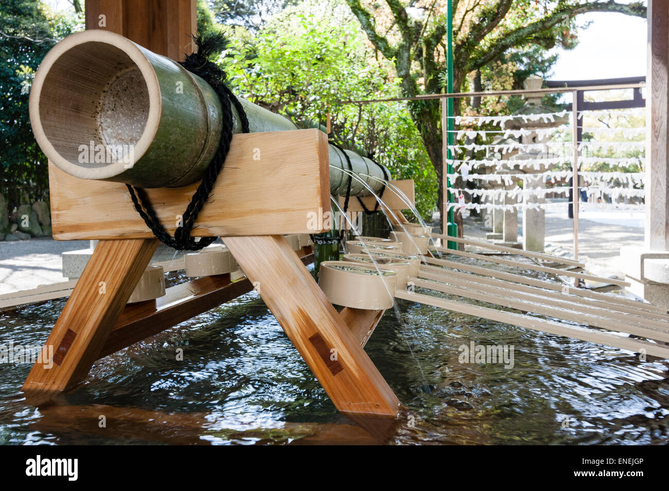 Schließen Sie Schöpfkellen und die Bambuspfeife auf einem Böll, mit Wasser Gießen aus Löchern in die Chozuya Wasserreinigungsfont an einem japanischen schintoistischen Schrein. Stockfoto