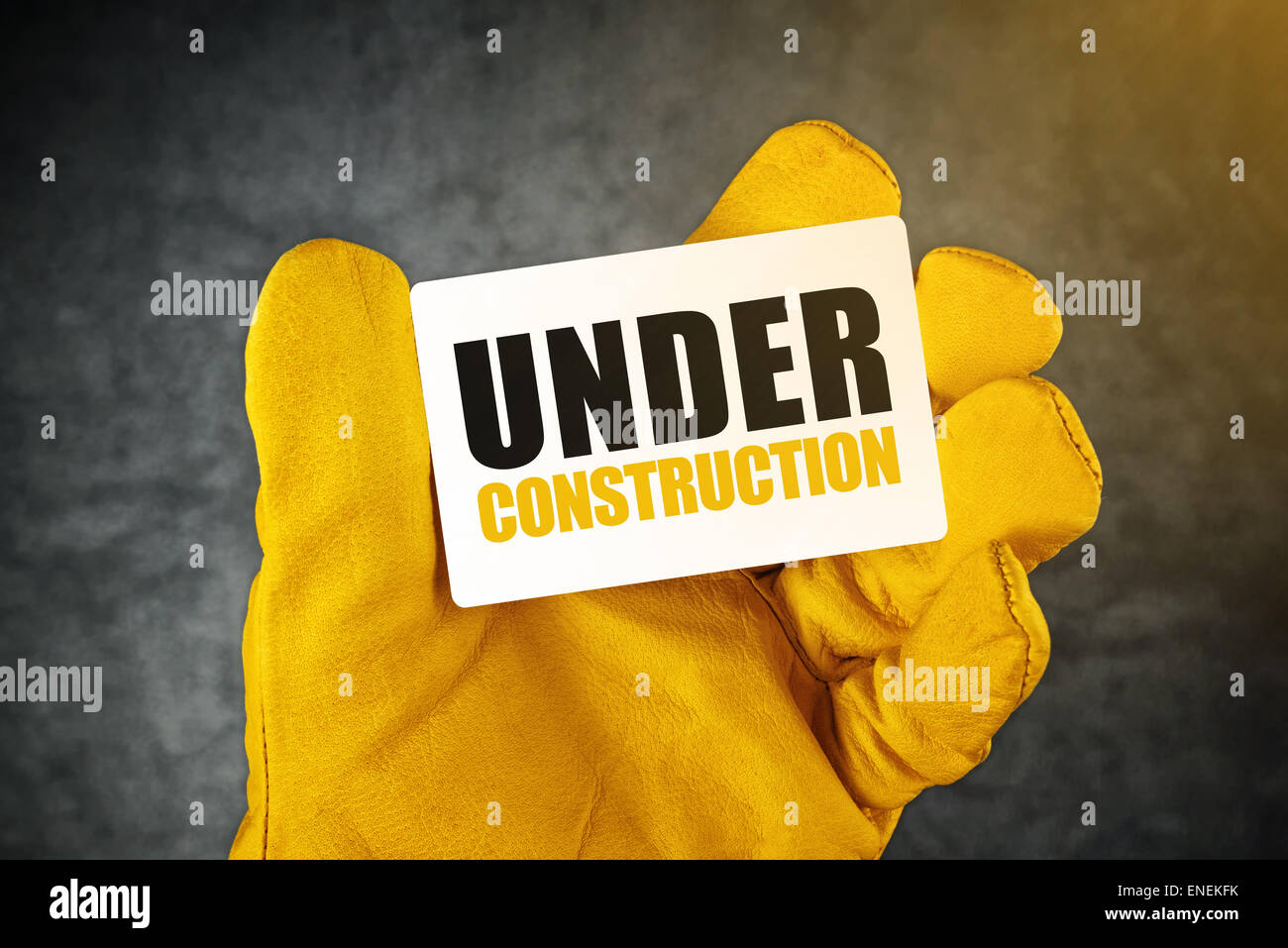 Under Construction auf Visitenkarte, männliche Hand in gelben Lederkonstruktion arbeiten Schutzhandschuhe hielt Karte Stockfoto