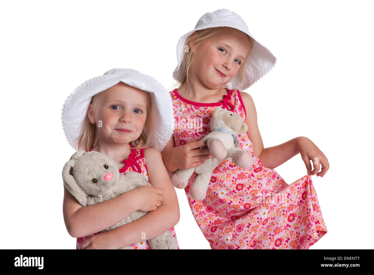 Porträt von zwei blonden Schwestern mit Hüten und Stofftiere auf weißem Hintergrund Stockfoto