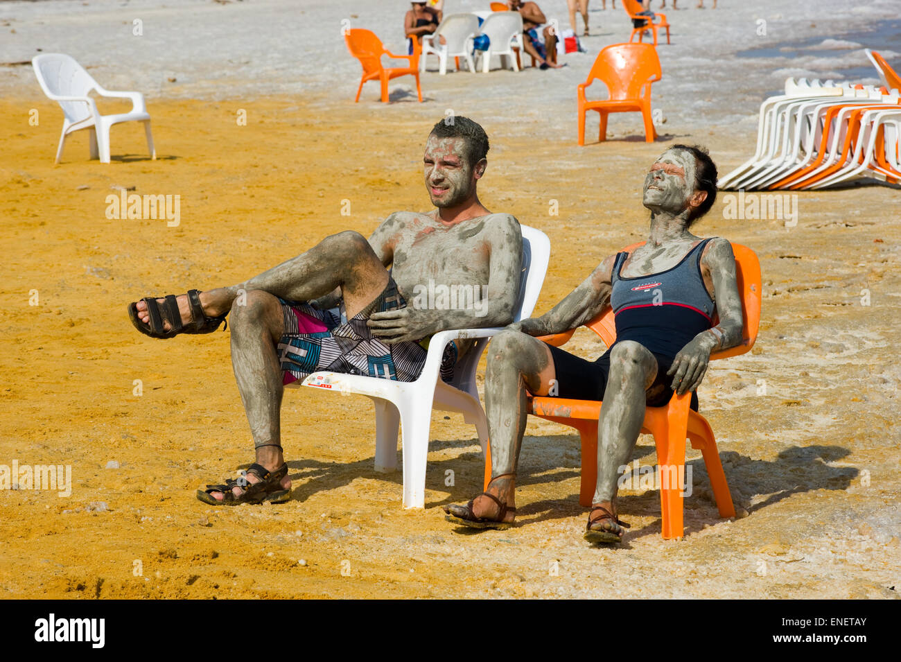 Totes Meer, ISRAEL - 13. Oktober 2014: Menschen entspannen, nachdem sie mit Schlamm am Strand des Toten Meeres in Israel eingerieben werden Stockfoto