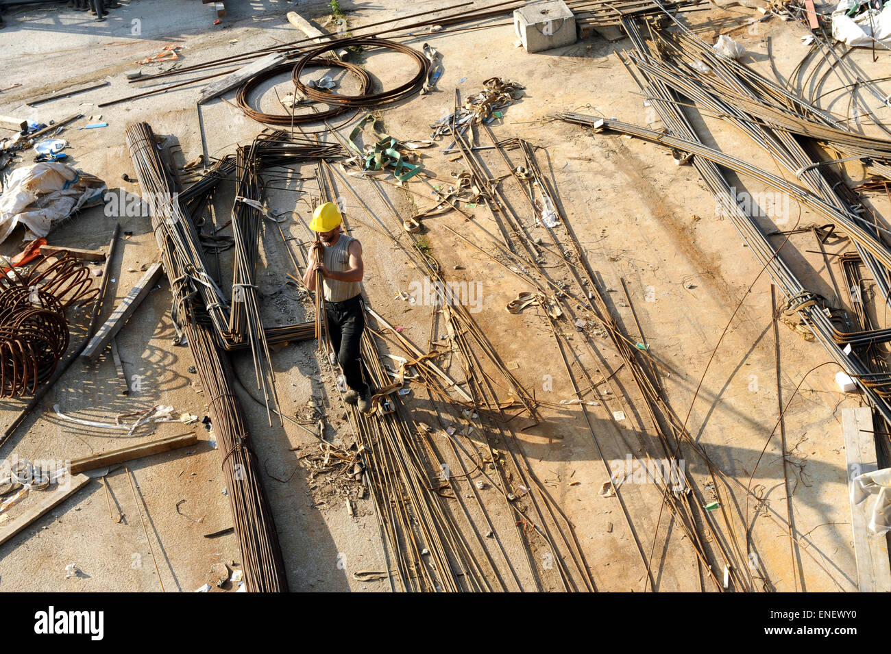 Workman, durchqueren einer industriellen Baustelle verstärkt über lange Stahl Armierungseisen ausgebreitet auf dem Boden, Luft Stockfoto