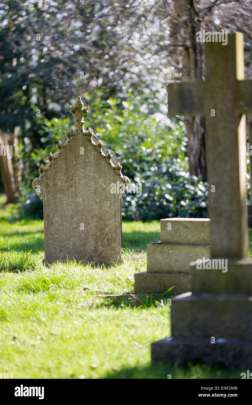 Eine alte zinnengekrönten Grabstein auf einem ländlichen Friedhof, getränkt in der Frühlingssonne. Stockfoto