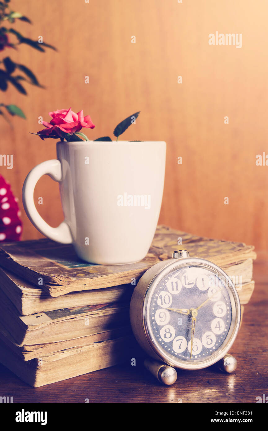 Tasse, Bücher und Blumen auf hölzernen Hintergrund. Romantische Kulisse in natürlichem Licht Stockfoto