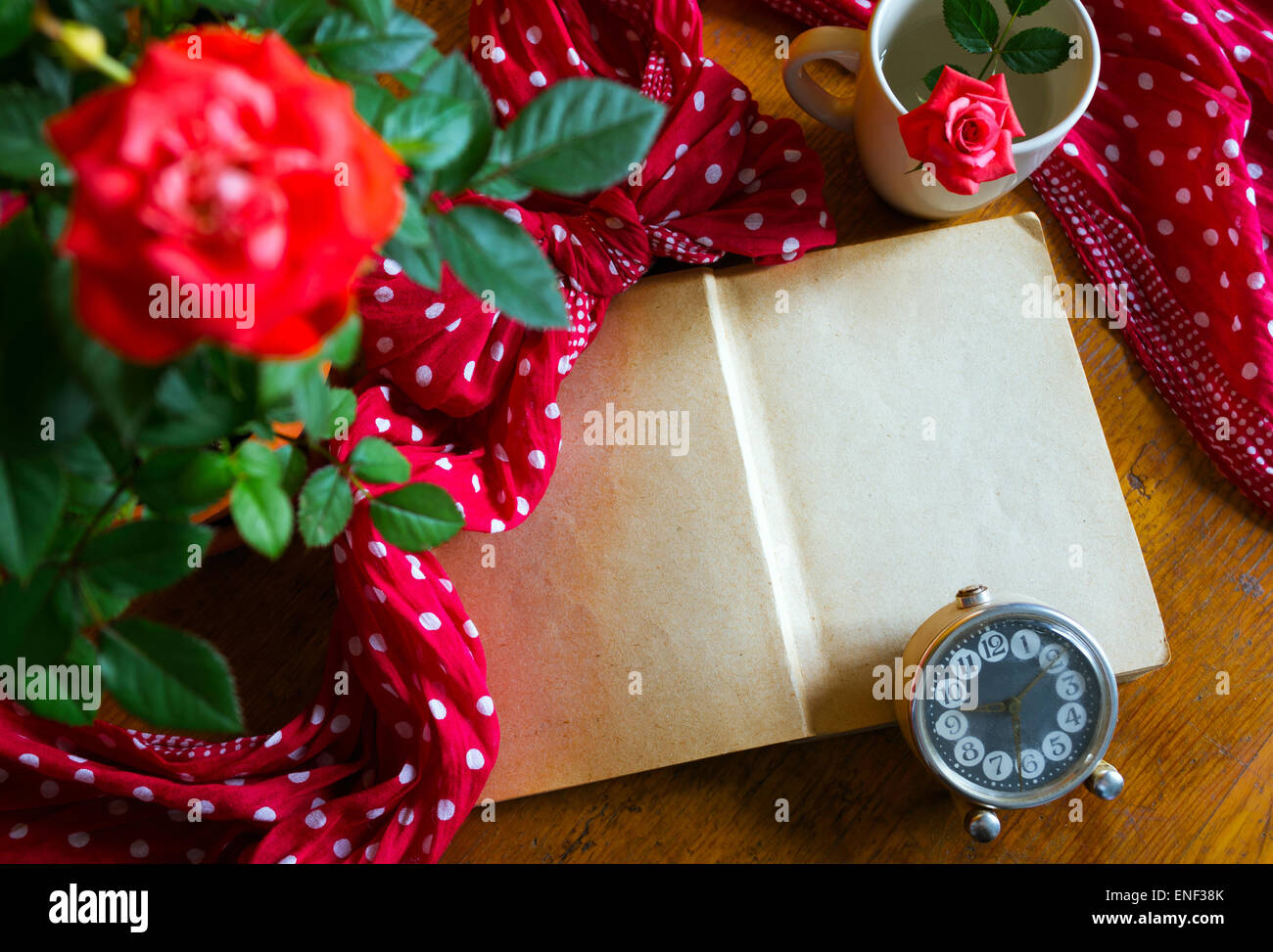 Altes Buch öffnen und Rosen auf hölzernen Hintergrund Stockfoto