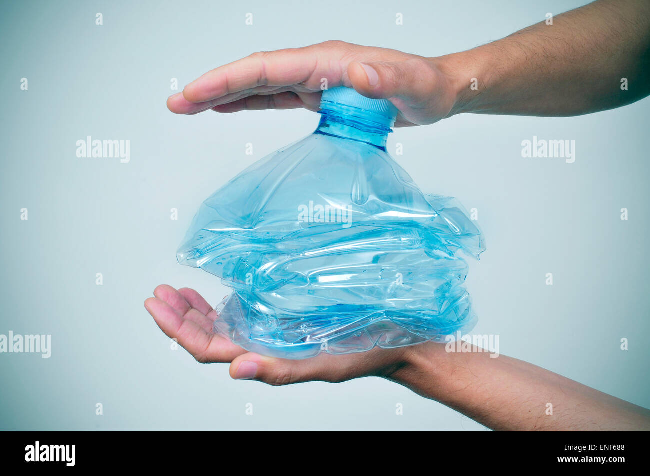 Closeup von einem kaukasischen Jüngling Zerschlagung einer Plastikflasche mit seinen Händen Stockfoto