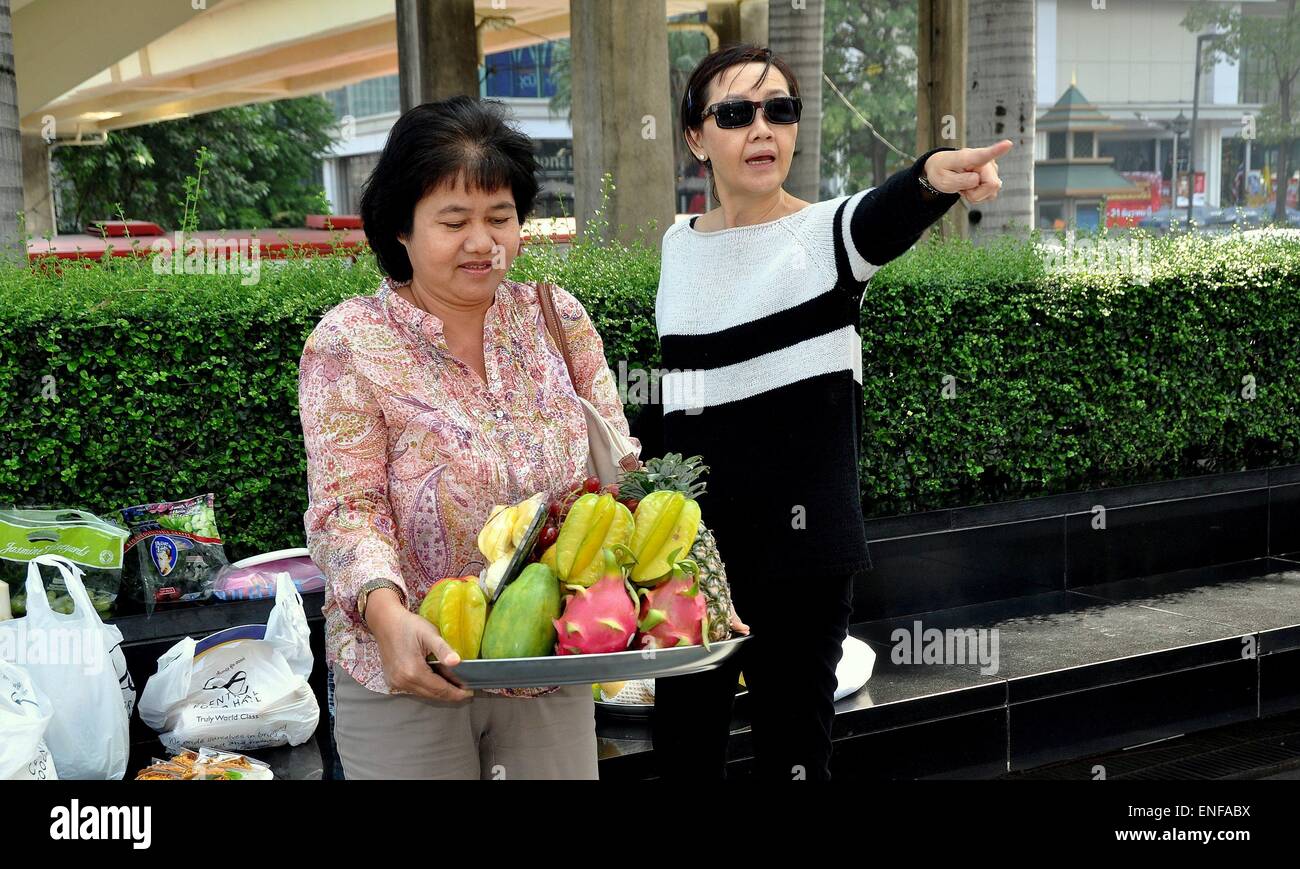 Bangkok, Thailand: Zwei Frauen mit einem Tablett mit tropischen Früchten Angebote an der hinduistischen Elefanten-Gott Ganesha-Schrein Stockfoto