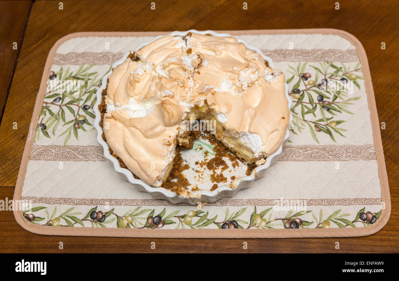 Frische, leckere hausgemachte Zitronen Baiser Torte in seiner Schale mit einer Scheibe herausgenommen Stockfoto