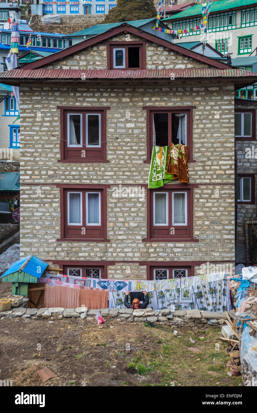 Eine nepalesische Frau Aufhängen von Wäsche auf der Wäscheleine, vor ihrem Haus in Namche Bazar Stockfoto