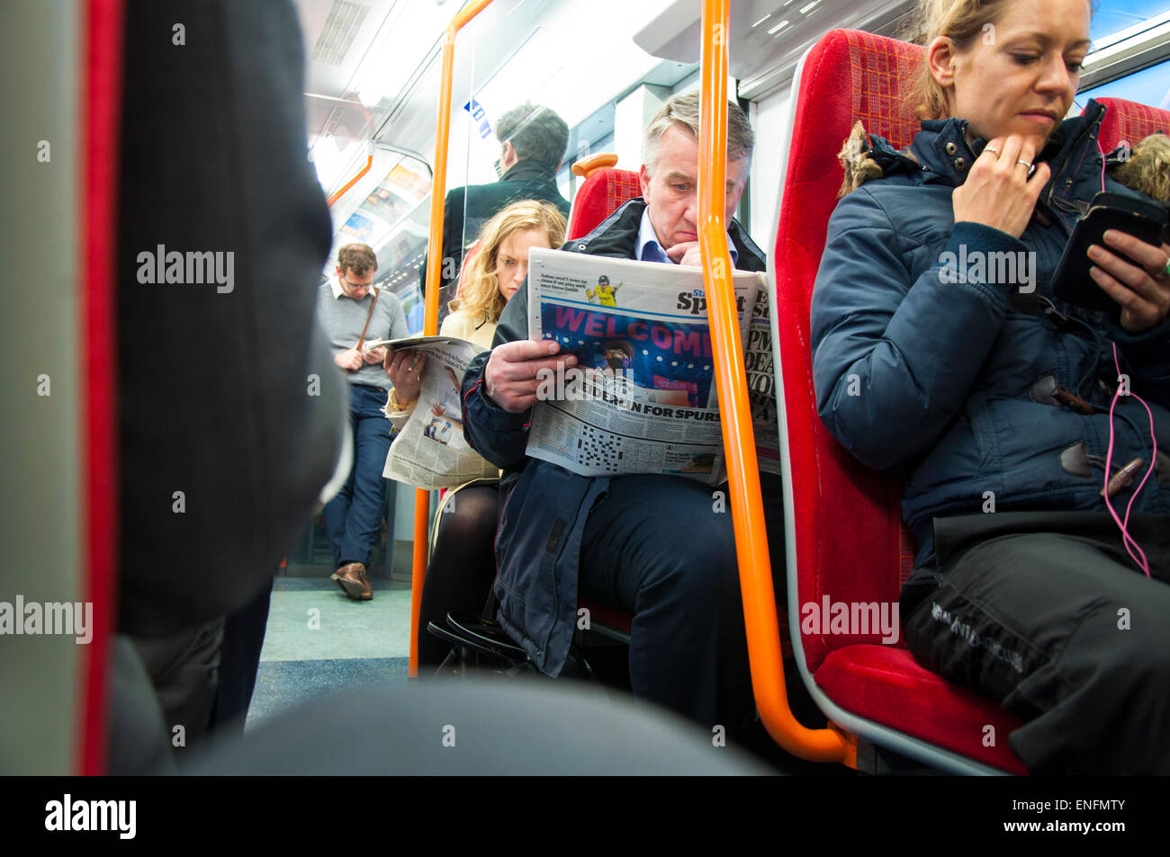 Pendler nach Hause mit dem Zug von London Waterloo lesen Zeitungen und iPhones und mobile Geräte Stockfoto