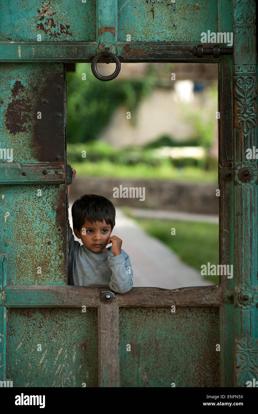 Kleiner Junge an einem Tor des Stadtschlosses, Udaipur, Rajasthan, Indien Stockfoto