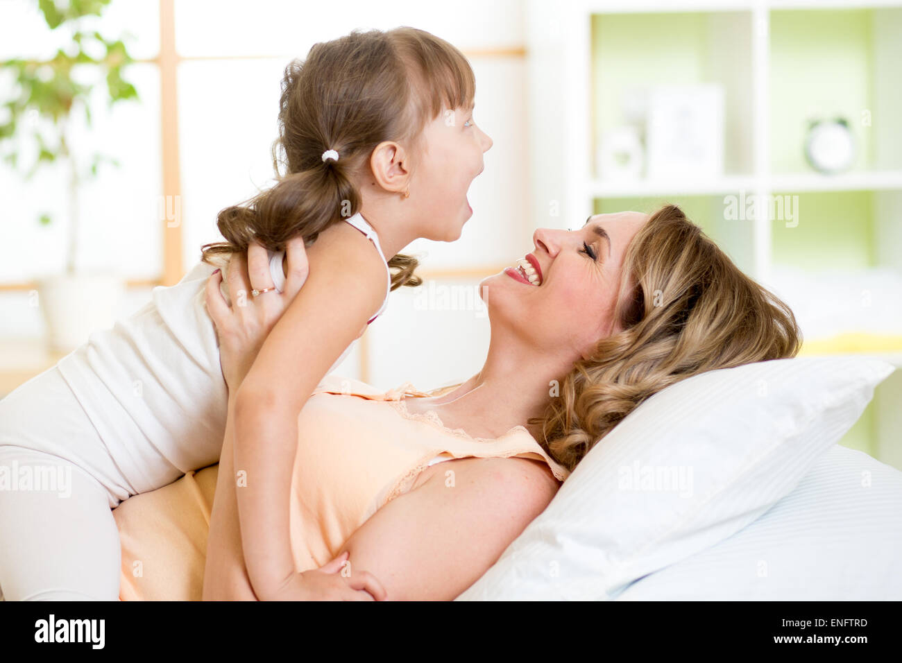 Glücklich im mittleren Alter Mutter mit der Tochter Kind im Bett genießen sonnige Morgen im Hause Schlafzimmer spielen Stockfoto