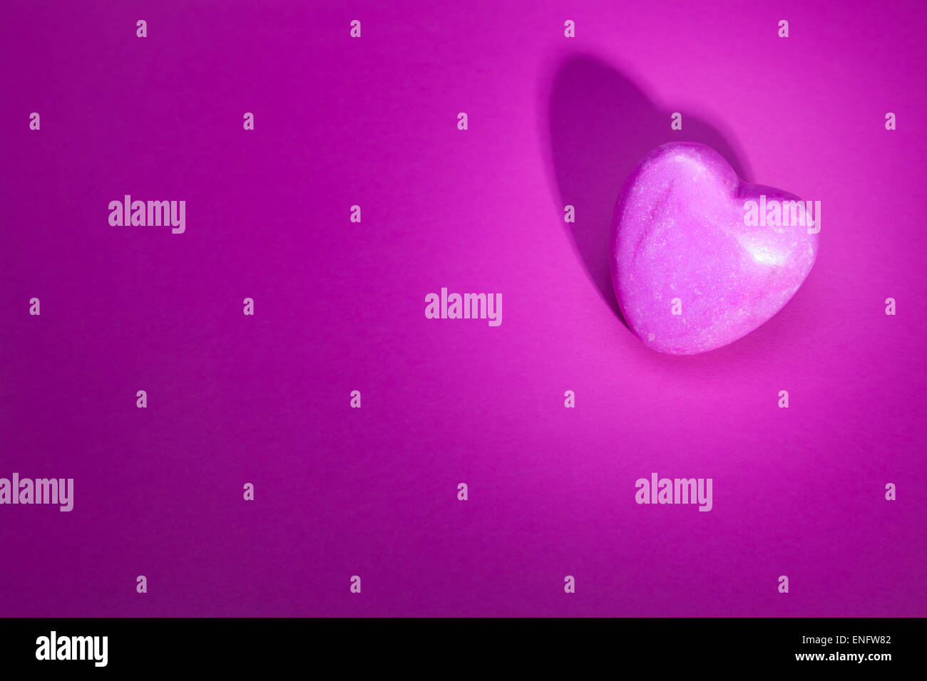 Eine beleuchtete rosa Stein Herz liegend auf rosa Hintergrund. Mit Exemplar Stockfoto