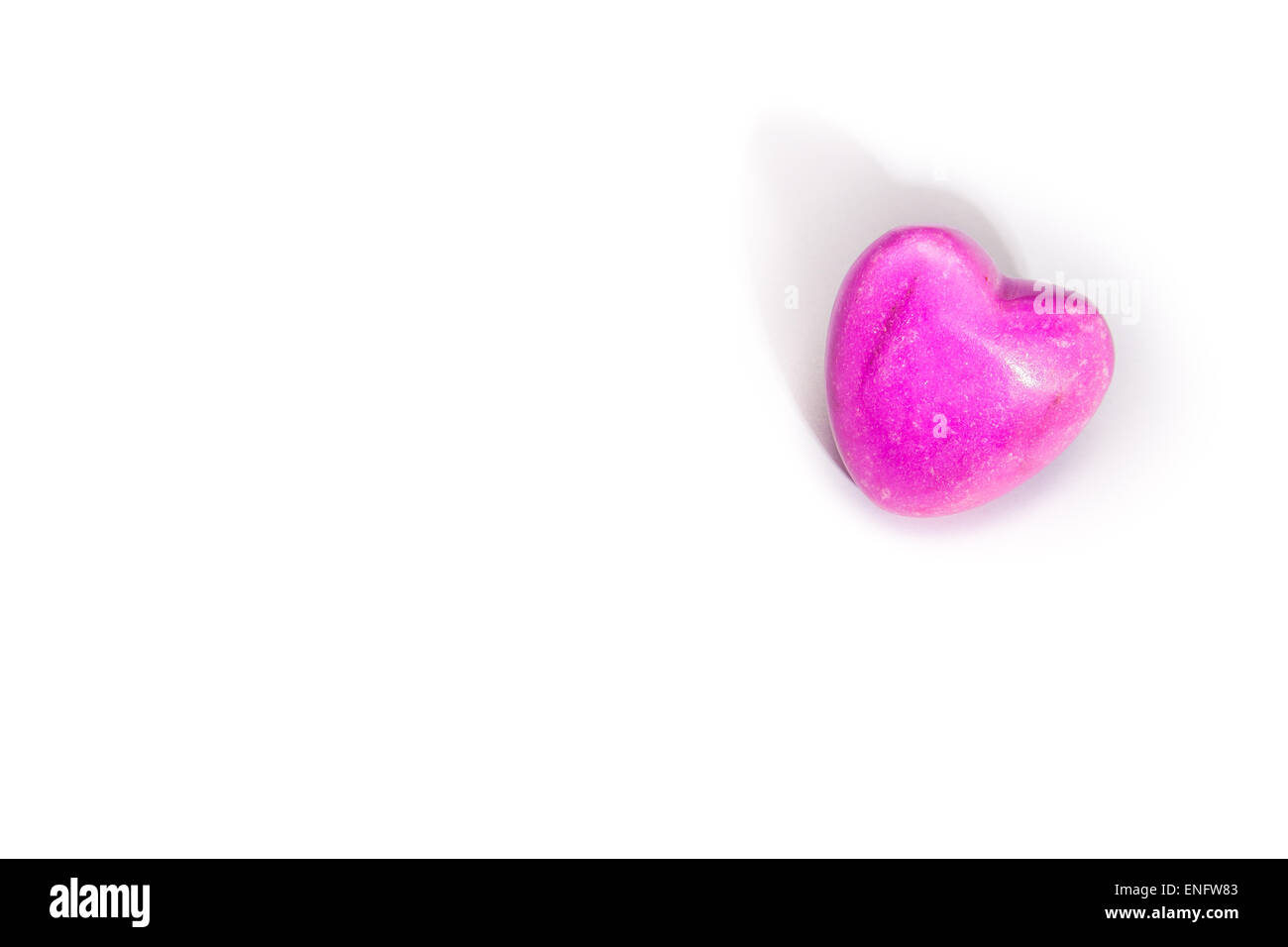 Eine beleuchtete rosa Stein Herz liegend auf weißem Hintergrund. Mit Exemplar Stockfoto