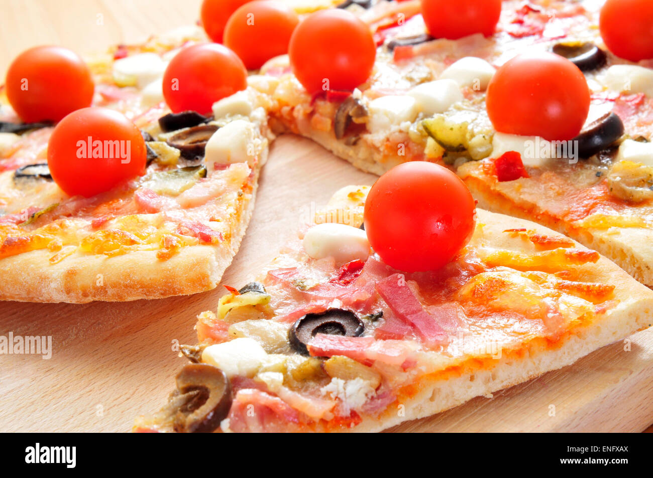 einige Scheiben von Pizza mit Speck, Oliven, Kirschtomaten, Ziegenkäse, Paprika und Auberginen Stockfoto