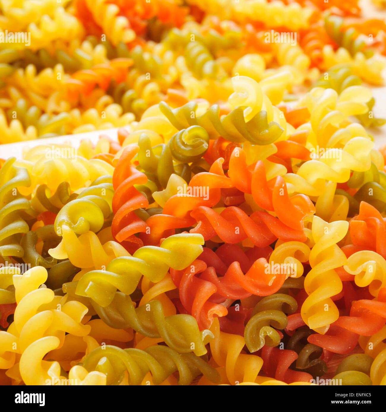 ein Haufen von rohem Gemüse Fusilli mit verschiedenen Farben: gelb wie gewohnt durch die Tomate rot und grün durch den Spinat Stockfoto