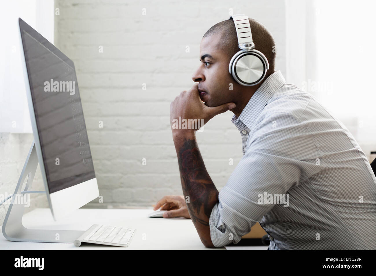 Gemischte Rassen Geschäftsmann Kopfhörer hören und arbeiten am Schreibtisch Stockfoto