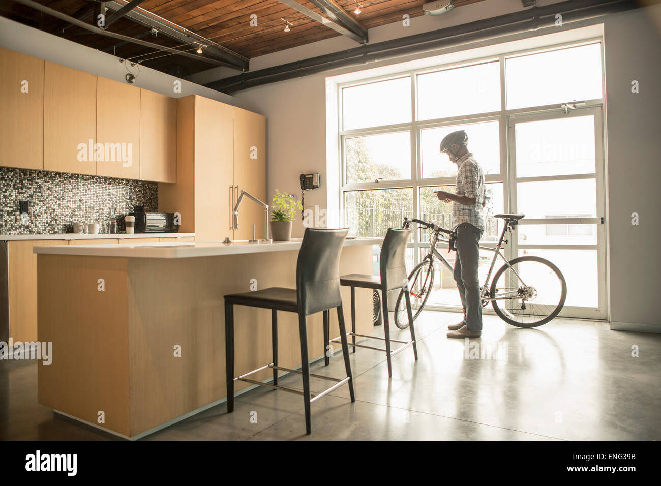 Schwarze Geschäftsmann mit dem Fahrrad mit Handy im Büro Küche Stockfoto