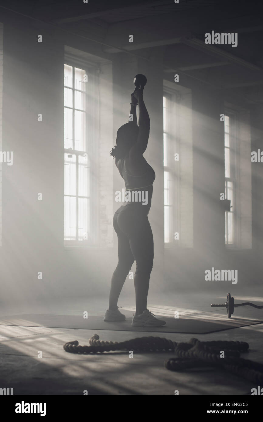 Schwarze Frau Heben von Gewichten in dunklen Turnhalle Stockfoto