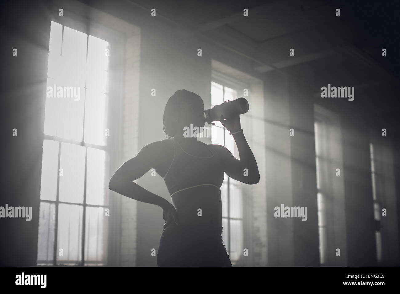 Schwarze Frau Trinkwasser Flasche in dunklen Turnhalle Stockfoto