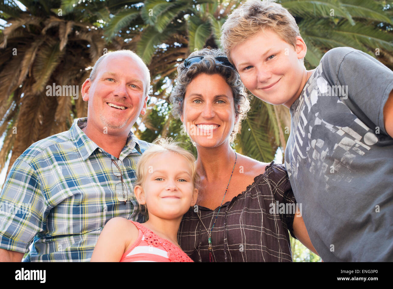 Kaukasische Familie lächelnd unter Palme Stockfoto