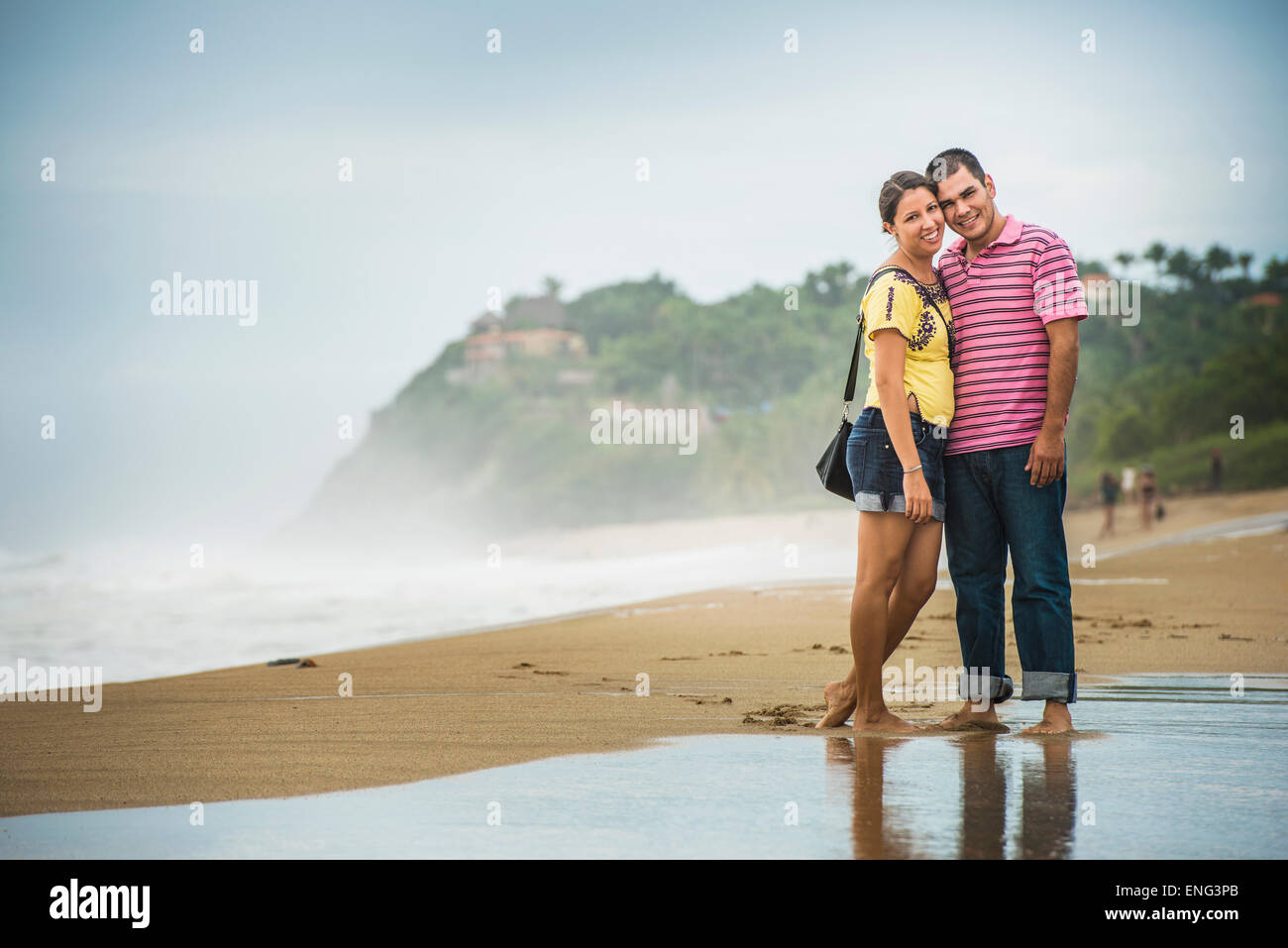 Hispanische paar umarmt in Wellen am Strand Stockfoto