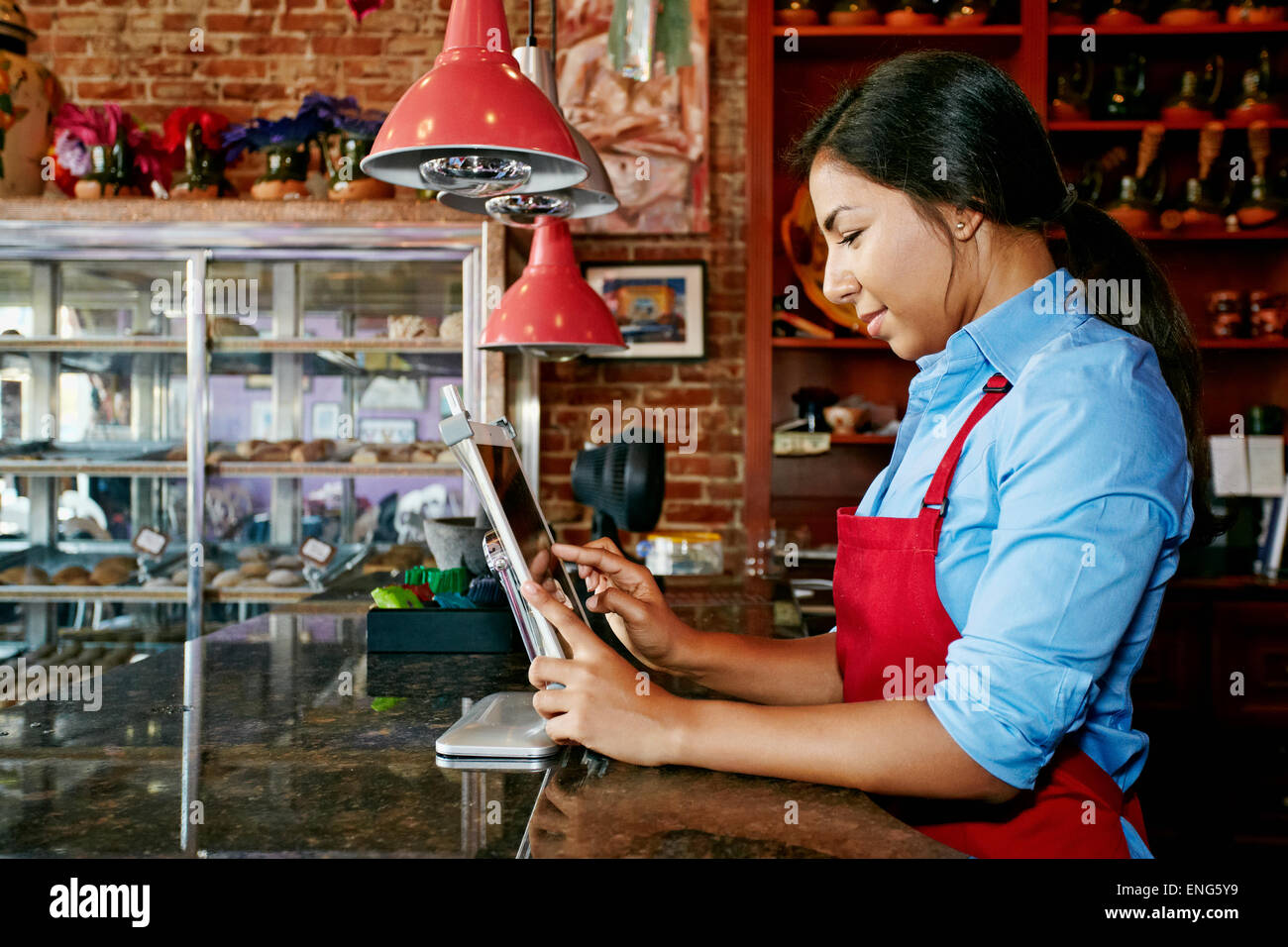 Hispanische Kassierer mit digital-Tablette registrieren in Bäckerei Stockfoto