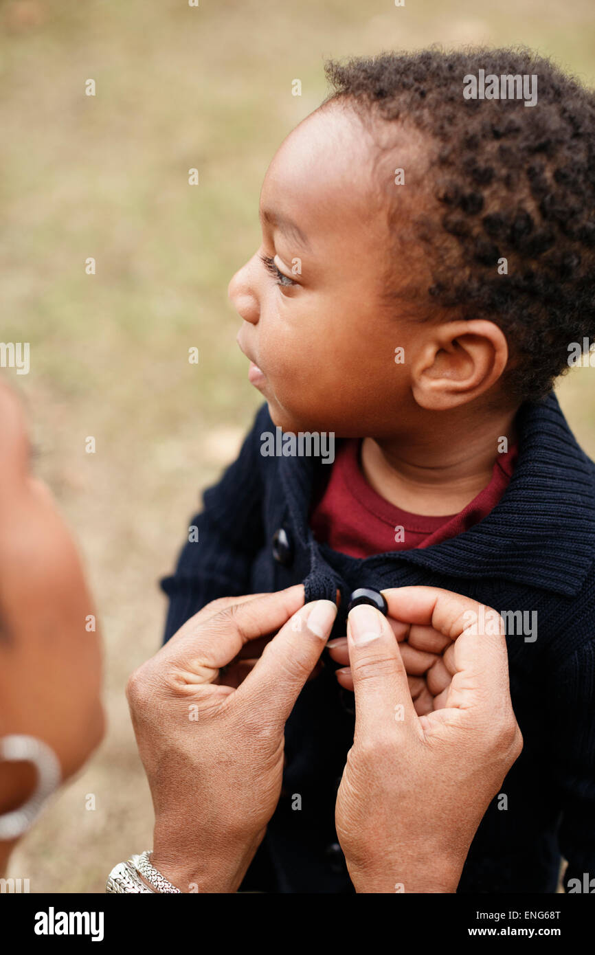 African American Mutter knöpfte Pullover von Sohn Stockfoto