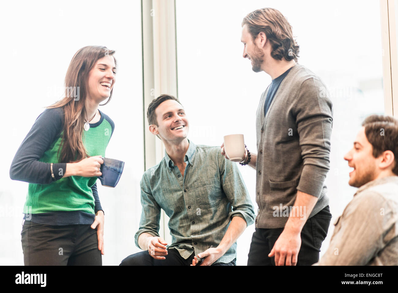 Vier arbeiten Kolleginnen und Kollegen auf eine Pause, gemeinsam lachen. Stockfoto