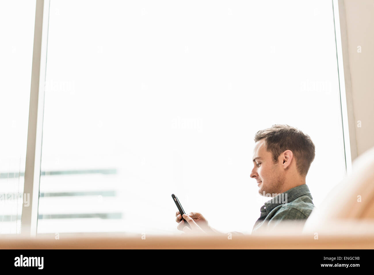 Ein Mann sitzt hält ein smart Phone, seine Botschaften zu überprüfen. Stockfoto